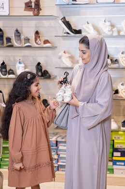 أم وابنتها عربيات تتسوقان في متجر أحذية