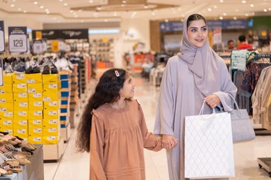 أم عربية وابنتها تتسوقان في متجر ملابس