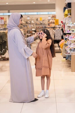 أم وابنتها تتسوقان لشراء نظارات شمسية في متجر ملابس