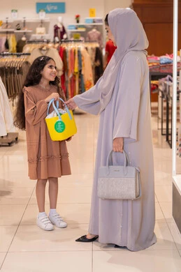أم وابنتها تتسوقان في متجر ملابس بملابس عربية