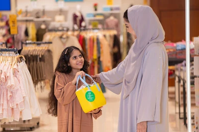 امرأة سعودية وطفلة مع حقيبة تسوق في المتجر
