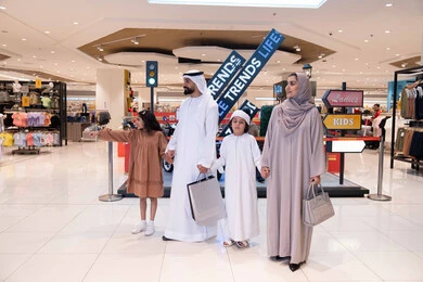 عائلة إماراتية تتسوق في مركز تجاري حديث مع حقائب