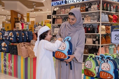 امرأة إماراتية وطفل يتسوقان لشراء حقائب مدرسية