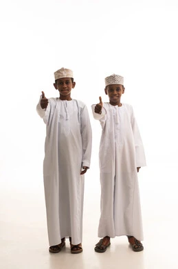 أطفال عمانيون بالزي التقليدي وعلامة الإعجاب بالإبهام