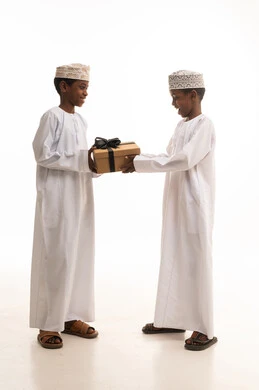 أولاد عمانيون بالزي التقليدي يتبادلون الهدايا