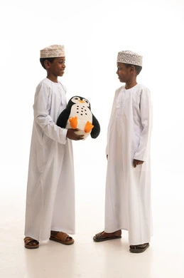 أطفال عمانيون بالزي التقليدي مع لعبة بطريق