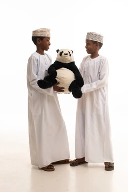 أطفال عمانيون بالزي التقليدي يمسكون لعبة باندا في الاستوديو