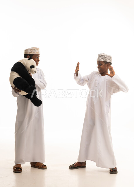 أطفال عمانيون بالزي التقليدي يلعبون بدمية في الاستوديو