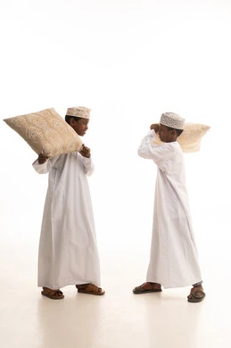 أطفال عمانيون بالزي التقليدي يلعبون بالوسائد