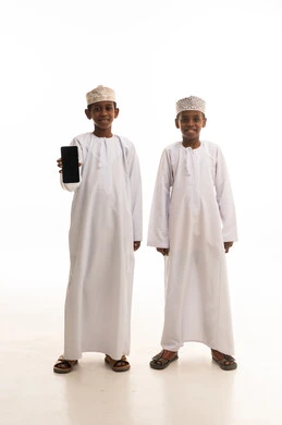 أطفال عمانيون بالزي التقليدي مع هاتف ذكي