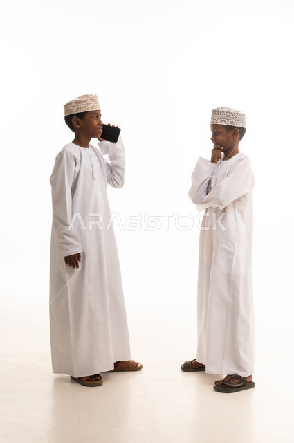أطفال عمانيون بالزي التقليدي يستخدمون الهاتف الذكي