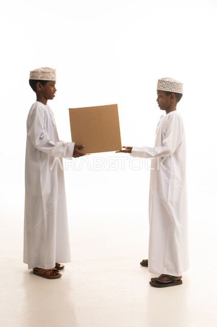 أطفال عمانيون بالزي التقليدي مع صندوق كرتوني