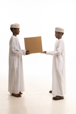 أطفال عمانيون بالزي التقليدي مع صندوق كرتوني