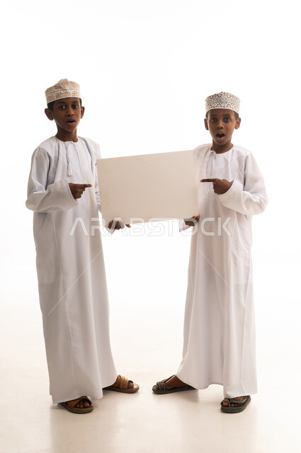 أطفال عمانيون يحملون لوحة بيضاء فارغة في استوديو