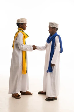 أطفال عمانيون بالزي التقليدي يتبادلون المصافحة