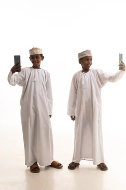 أطفال عمانيون بالزي التقليدي يلتقطون صور سيلفي