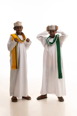 أطفال عمانيون بالدشداشة والكمة التقليدية خلفية بيضاء