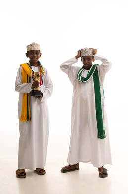 أطفال عمانيون بالزي التقليدي يحملون كأساً ذهبياً