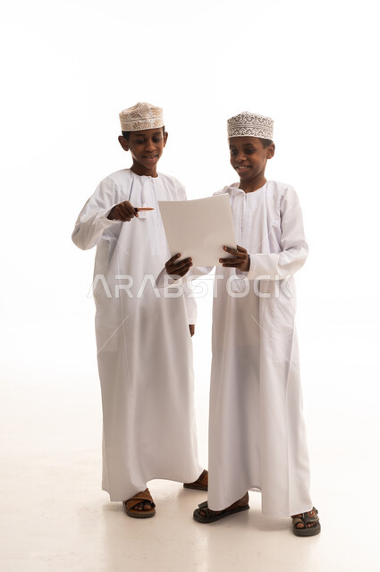 أطفال عمانيون بالزي التقليدي يقرأون خلفية بيضاء