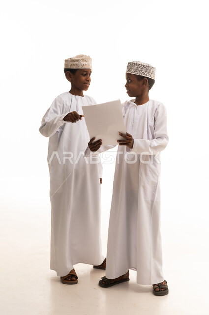 Omani Boys in Traditional Dress Reading Paper