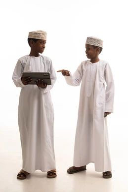 أطفال عمانيون بالزي التقليدي يستخدمون جهاز لوحي