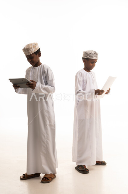 أطفال عُمانيون يستخدمون الجهاز اللوحي والورق