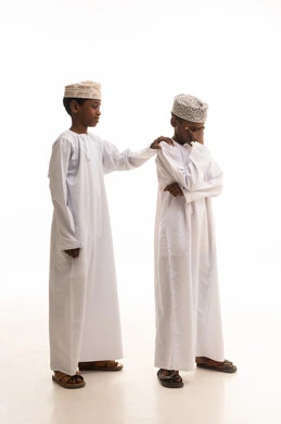 أطفال عمانيون بالملابس التقليدية في وضعية مواساة