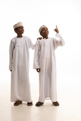 أطفال عمانيون بالزي التقليدي يشيرون للأعلى