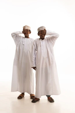 طفلان عمانيان بالزي التقليدي أمام خلفية بيضاء