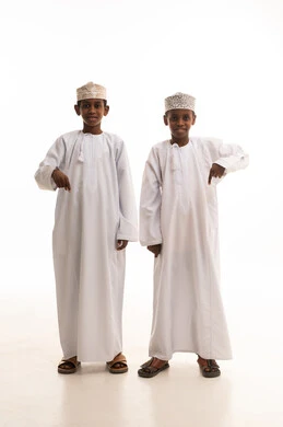 أطفال عمانيون بالزي التقليدي يشيرون نحو الأسفل