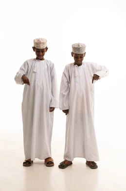 أولاد عُمانيون بالملابس التقليدية يشيرون للأسفل