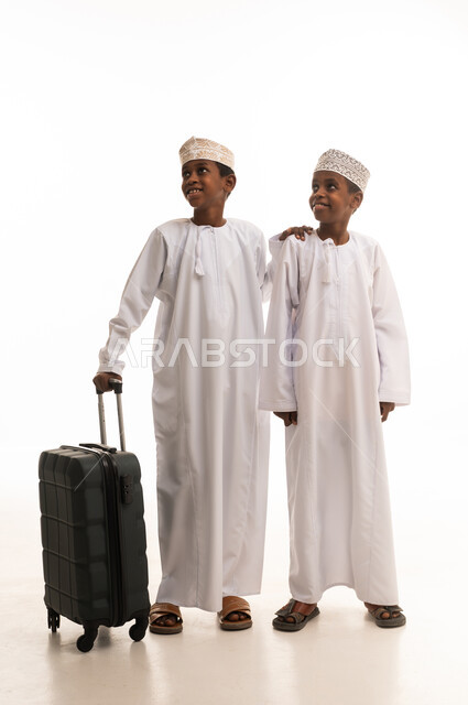 أطفال عمانيون بالزي التقليدي مع حقيبة سفر