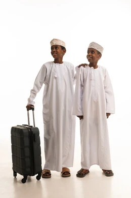أطفال عمانيون بالزي التقليدي مع حقيبة سفر