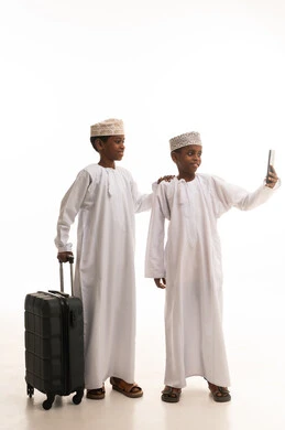 أطفال عمانيون مع حقيبة سفر يلتقطون سيلفي