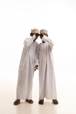 أطفال عمانيون بالزي التقليدي يستخدمون المنظار