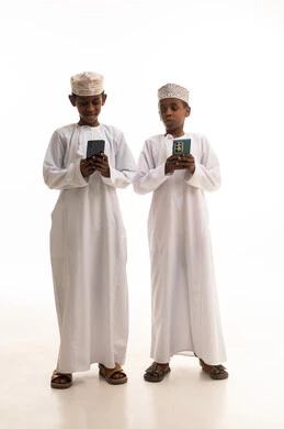 أطفال عمانيون بالزي التقليدي يستخدمون الهواتف الذكية