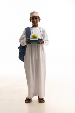 طالب عماني مع صندوق غداء وتفاحة على خلفية بيضاء