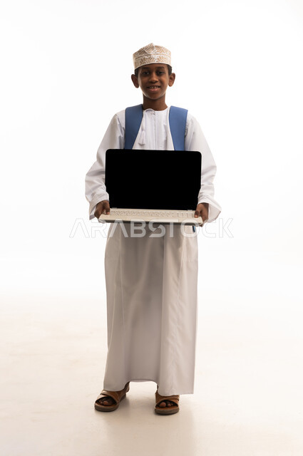 طالب عماني يحمل كمبيوتر محمول على خلفية بيضاء