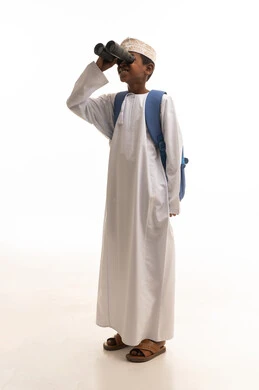 طفل عماني بالزي التقليدي يستخدم المنظار