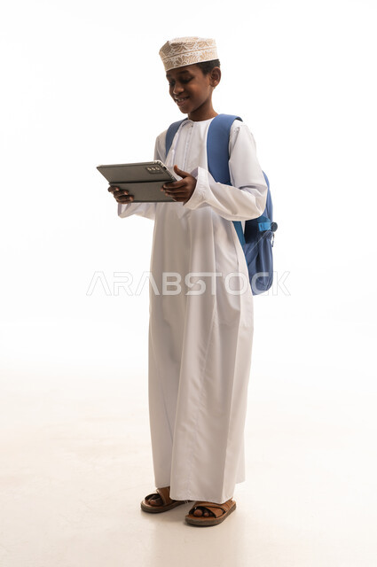 طالب عُماني يحمل جهاز لوحي وحقيبة ظهر
