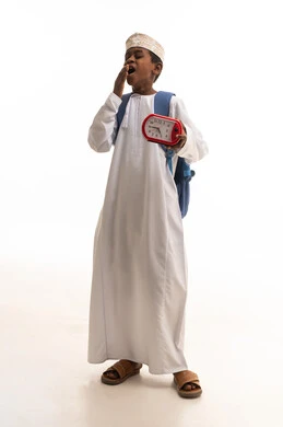 طالب عماني يتثاءب مع ساعة منبه وحقيبة