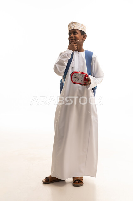 طالب مدرسي عماني يحمل ساعة منبه في الاستوديو