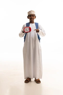 طالب عماني بالزي التقليدي مع ساعة منبه