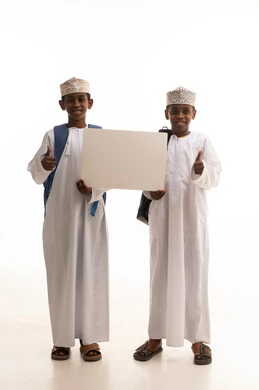 طلاب مدارس عمانيون يحملون لوحة بيضاء فارغة