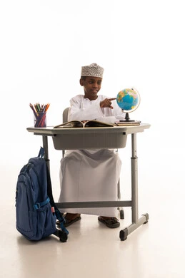 طفل عماني يشير إلى الكرة الأرضية في استوديو