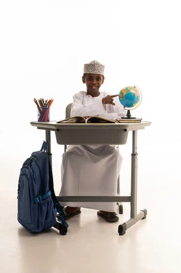 طالب عماني على مقعد دراسي مع مجسم الكرة الأرضية