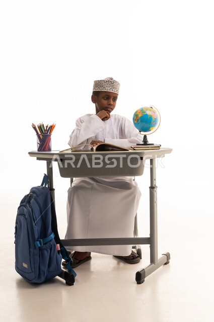 طالب عماني خلف مكتبه مع مجسم الكرة الأرضية