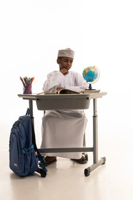 طالب عماني خلف مكتبه مع مجسم الكرة الأرضية