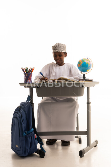 طالب عماني صغير يكتب على مقعده الدراسي