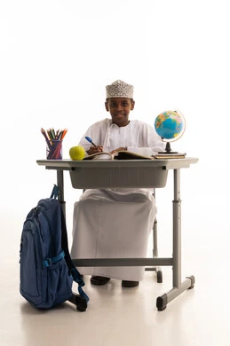 طالب عماني يكتب على مقعد مدرسي خلفية بيضاء